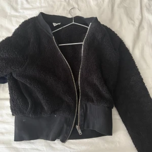 Svart Teddy Jacka - Svart kort teddy jacka i storlek XS från Gina tricot. Använd men i gott skick, det vita på jackan är bara ludd och lite djurhår och jackan klädrullas såklart innan den skickas! 🩵Supersöt nu till hösten !