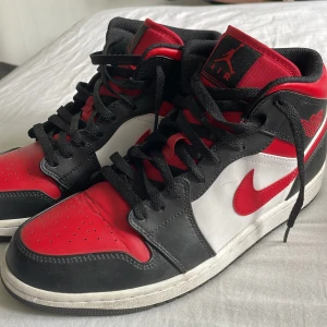 Nike Air Jordan 1 High red toe - Säljer ett par Nike Air Jordan 1 High med klassisk färgblockning i rött, svart och vitt. Skorna har snörning, rund tå och platt sula. Ikonisk Swoosh i rött på sidan och Air Jordan-logga på ankeln. Tillverkade i skinn med perforerad tåbox för extra ventilation. Passar även 43