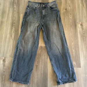 Baggy jeans från H&M i grått - Säljer ett par gråa baggy jeans från H&M i storlek 31/32. De har klassisk femficksdesign, raka ben och en avslappnad passform. Jeansen är tillverkade i denim och har en snygg tvättad look med ljusare partier framtill och baktill. Nya utan pris lapp och tvättad en gång