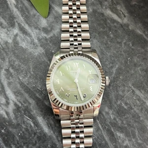 Silverfärgad Seiko automatisk klocka - Stilren Seiko automatisk klocka i silver med klassisk jubilee-länk och räfflad bezel. Modellen heter arabic dial! Storlek 36mm. Bandet har tyvärr gått sönder men det är väldigt lätt att fixa, alla klockbutiker erbjuder det. 
