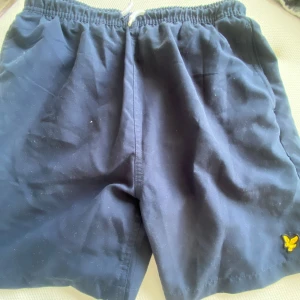 Mörkblåa badshorts från Lyle & Scott - Snygga mörkblåa badshorts  från Lyle & Scott. Mycket fint skick och väldigt fina i modellen. Storlek 12-13 år 