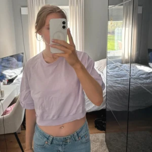 Ljuslila croppad t-shirt - Säljer en ljuslila croppad t-shirt med korta ärmar och rund hals. Toppen har en loose passform och är perfekt för dig som gillar en avslappnad stil. 