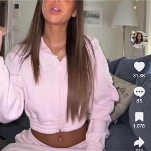 Ljusrosa croppad hoodiejacka Hoodrich - Säljer en ljusrosa croppad hoodiejacka från Hoodrich med broderad logga framtill. Jackan har huva, dragkedja, långa ärmar och elastisk midja. Perfekt för chill dagar och streetstyle. Fickor framtill och cool detalj på ärmen.