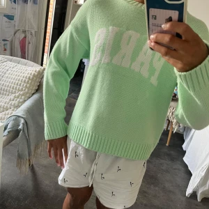 Mintgrön stickad tröja från ASOS - Superfin mintgrön stickad tröja från ASOS DESIGN med vit text 'PARIS' framtill. Tröjan har rund hals, ribbade muddar och är lite loose i passformen. Perfekt att slänga på sig när det är lite kyligt ute. Snygg att styla med jeans eller kjol.