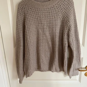 Beige stickad tröja från 157 - Säljer en beige stickad tröja från 157 i storlek M. Tröjan har ett grovt, luftigt stickat mönster och bred ribbad kant vid halsen, ärmslut och nederkant. Perfekt för dig som gillar chill och enkel stil under höst och vinter.