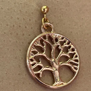 By prisförslag- 1 st Guldörhänge med livets träd - Unikt örhänge i guldton med ett detaljerat livets träd i rund ram. Hängsmycket har en snygg, öppen design som ger en cool och bohemisk vibe. Perfekt för dig som gillar symboliska smycken och vill sticka ut med något personligt.