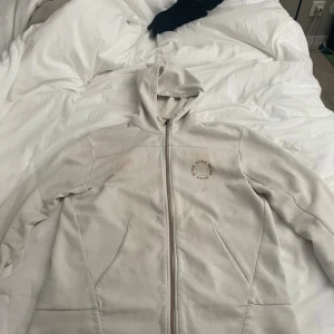 Vit zip hoodie från BOSS - Säljer en stilren vit hoodiejacka från BOSS med dragkedja framtill och huva. Jackan har diskret logga på bröstet och två fickor på sidorna. Perfekt för en avslappnad och sportig look. Snörerena saknas, helt ok skick, storlek M, nypris 2000kr, priset kan diskuteras