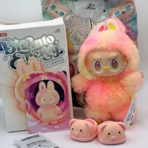 Äkta Labubu Loyalty Pop Mart Big Into Energy  - Supergulliga Big Into Energy Labubun Loyalty köpt från Pop Mart  Hon är äkta med streckkod på sin etikett och på kartongen Du kan själv verifiera henne på deras sida med hjälp av koden på hennes etikett Hon har vridbart huvud, händer och fötter samt böjbara armar Hon är helt ny, endast öppnad & fotad Loyalty får med sig ett par jättesöta rosa gris gummi tofflor Dom är lite stora, men hon står jättebra i skorna Hon får oxå med sig sin orginalkartong, foliepåse & Loyalty kortet Kartong & påse är d