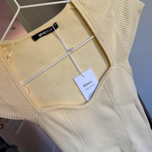 Ljus ribbad topp från Gina Tricot - Supersnygg ljusgul ribbad topp från Gina Tricot i storlek XS. Den har hjärtformad urringning och är tillverkad i ett mjukt, stretchigt material med EcoVero. Perfekt för dig som gillar stilrena och fräscha plagg med modern passform.