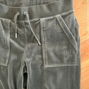Gröna mjukisbyxor Juicy Couture - Snygga gröna mjukisbyxor från Juicy Couture med bred resår i midjan och snörning framtill. Byxorna har stora fickor både fram och bak, bakfickorna har lock med knappar. Jag har sytt upp dom eftersom dom va för länge för mig. Dom passar mig som är 1,63! Finns inga märken på 