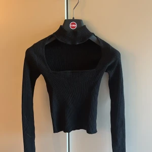 Svart ribbad polotröja med öppet fram till - Säljer en svart ribbad polotröja från Bershka med lång ärm. Tröjan har en croppad passform och är tillverkad i mjukt stickat material. Den är väldigt liten i storlek, aldrig använd💕