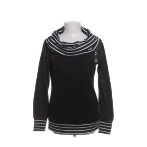 Svart tröja med randig krage från Lucky - Snygg svart tröja från Lucky med en unik randig krage och knapprad detalj på sidan. Tröjan har långa ärmar och randiga muddar vid ärmslut och nederkant. Perfekt för en stilren look, går även att ha som en off shoulder❤️