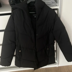 Snygg svart jacka - Snygg svart jacka. Använda några gånger men i fint skick! Finns även midjeband som man får med! Liten i storlek, storlek 40, men passar mig som annars har XS/S