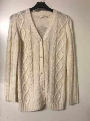 Vacker vintervit kofta  - Snygg och mjuk stickad kofta som passar till det mesta. Vackert flätmönster framtill och slätstickad på baksidan.  Storlek 146-152 men stor i storleken och kan jämföras med en S eller XS