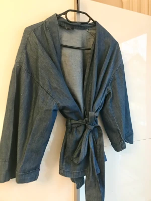 Kimono jeans strl. 34 - Fin blus/kimono i jeanstyg inköpt på Bubbleroom. Storlek 34. Använd ett fåtal gånger så inga tecken på användning.   100 % bomull