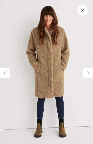 Ny teddykappa, aldrig använd. - Aldrig använd. Lappen kvar!   Nypris 999:-  Mitt pris 500:-  Kappa i teddymaterial med ståkrage. Rak passform med fickor i sidorna. Dragkedja med dold knäppning. Längden följer storleken ca 100-108 cm från axeln. • Fodrad