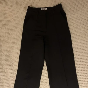 Kostymbyxor  - Svarta, högmidjade kostymbyxor från Madlady. Använda men i fint skick. Säljes då de är på gränsen till för korta för mig. Storlek 32, L30. Köptes för 599 kr.