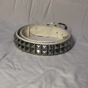 Vitt Nitbälte - Ett coolt vitt nitbälte! Lite slitningar här och var men endast på insidan av skärpet. 