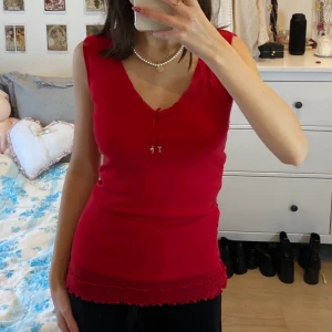 rött linne - Jättefint rött linne med volang och två små metallhängen längst fram, insydd för att passa xs. Möts i slussen eller postas🤎 Köp nu är på