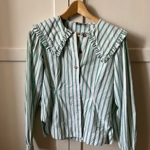 Ganni - Grön/vit randig skjorta med stor krage från Ganni. Säljes pga används inte lika mycket längre. I fint skick, inga skavanker.