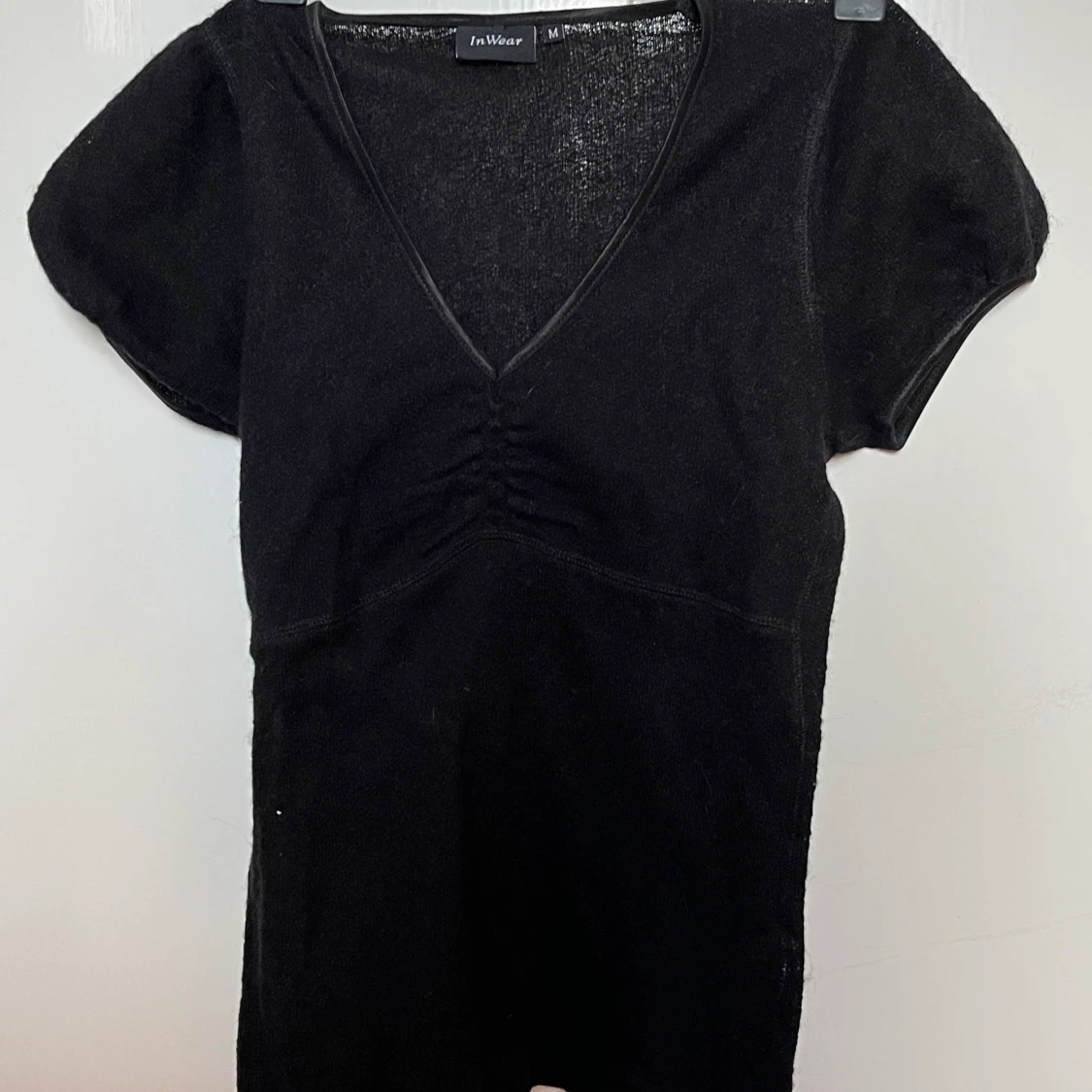 stickad svart topp som är rynkad 