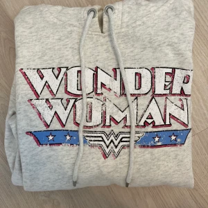 Hoodie med tryck - En hoodie med trycket ”Wonder Woman”. Står att det är storlek S, men skulle nog säga att den är mer som en XS