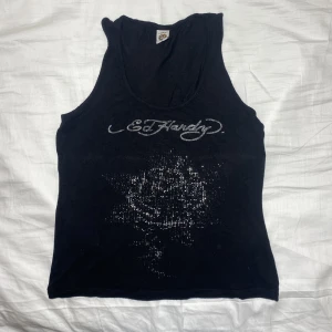 Ed hardy linne  - Kattigt y2k Ed Hardy linne. Skönt stretchigt material. Okej vintage skick, många rhinestones har åkt av eller är påväg att åka av och resåren (?) på insidan är lite sliten. Andra deflekter syns på bilderna. Köps via Swish (frakt 54 kr) eller köp nu 💋