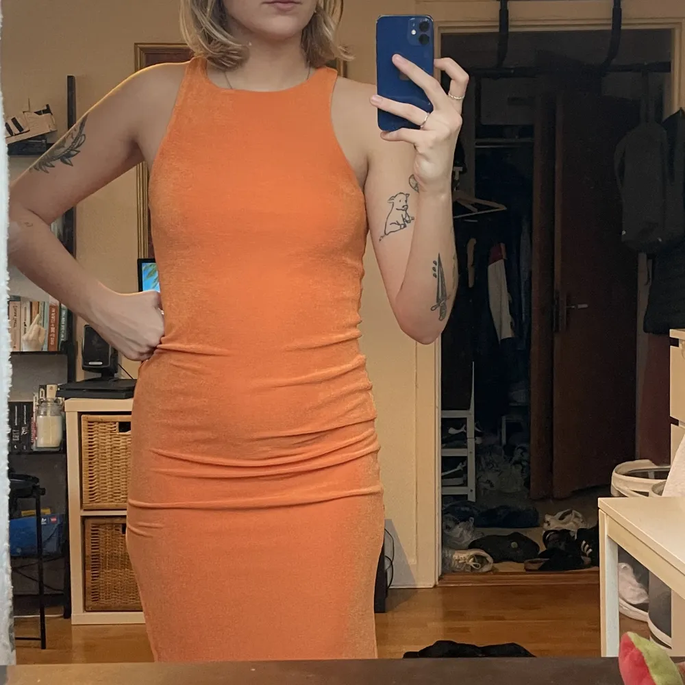 Super fin klänning i skimrande orange! Har en slits på vänster sida. Den har även en underkjol så den inte blir genomskinlig!. Klänningar.