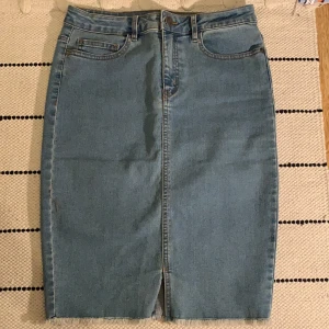 Medellång tajt jeanskjol - Medellång kjol köpt på VeroModa, från märket Noisy May. Storlek M, tajt passform, tunt material och i en ”mellanblå” färg. Längden är ca 56 cm. Aldrig använt! 