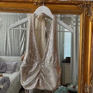 Glittrig Festtopp - Superfin glittrig festtopp med öppen rygg. Säljer då mina bröst är för små för att den ska sitta. Storlek S/M. 