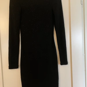 Klänning - En klänning som glittrar passar perfekt till jul eller nyår. Använd ca 2 gånger. Den har även en fin u rigning bak i ryggen. Passar även för de som har storlek s