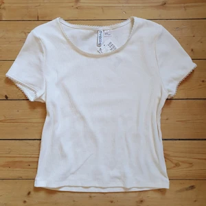 Vit ribbad t-shirt - En benvit ribbad t-shirt med söta detaljer vid kragen och ärmarna! Köpte för några år sedan men inte använt, prislappen är kvar ☺
