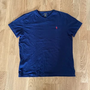 Polo t shirt  - En mörkblå polo t shirt som är V ringad. Storleken är M 