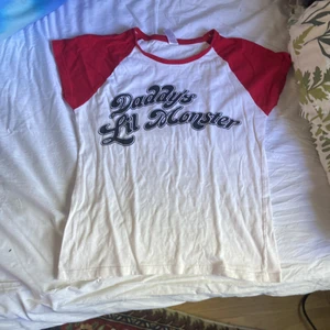 Harley Quin t-shirt - En vit och röd tröja med texten Daddys little monster i svart på, storlek M