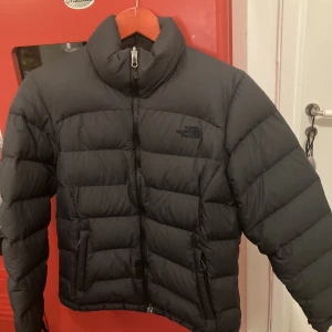 The North Face Jacka - En helsvart north face jacka, inte så använd. Har även tvättat och fräschat upp den! Det enda som är lite märkbart med den är att det finns en tejp bit som håller igen ett hål. (kan se på första bild) Storlek M Women, men passar som S på män också:)