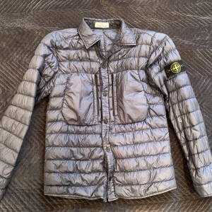 Stone Island Jacka - Säljer nu den perfekta vår/höst-jacka från Stone Island. Inköpt på NK för lite mer än 6000kr.  Den är använd endast fåtal gånger därav det magnifika skicket. Jackan är i storlek Large. Den innehåller dun så du håller dig varm även i vindarna.