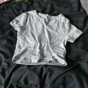 En grå t shirt med en slits vid nackdelen