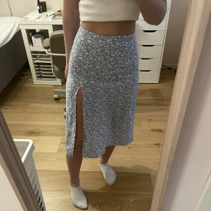 Blå blommig kjol - Jättefin blå blommig kjol som tyvärr är för liten för mig. Jättefint skick. Stängs med dragkedja