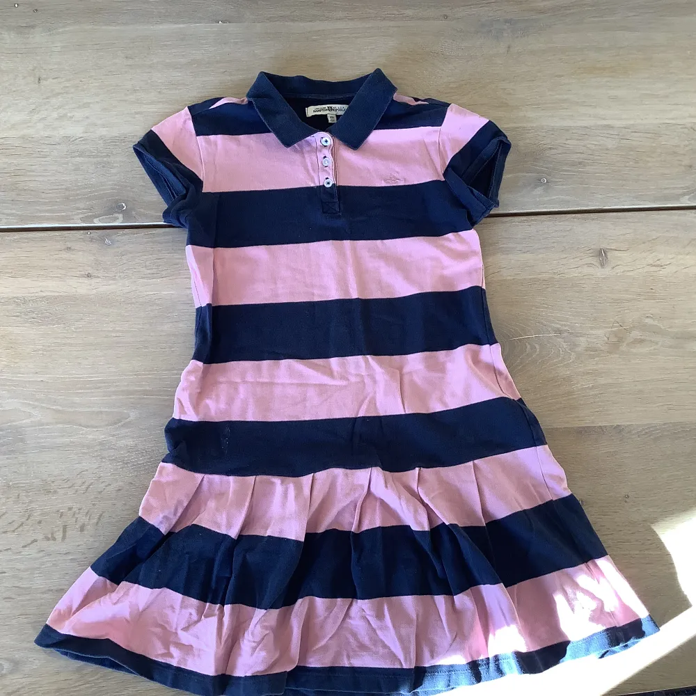 Det är en mörkare blå och rosa randig klänning från Lindex. Den är ganska använd, den är i storleken 146-152.. Klänningar.