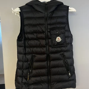 Moncler väst i stl S oanvänt - Moncler väst i stl S, helt oanvänt!   Har tyvärr inte lappen kvar till den. Köptes för nått halvår sen men har bara hängt i garderoben och aldrig blivit använd.  Finns kvitto!  Värd: 7500:-