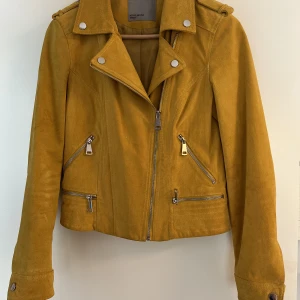 Mockajacka  - En slutsåld senapsgul äkta mockajacka i bikermodell. Sjukt snygg! Den är ganska liten i storleken så skulle säga att den är en S/M . Sparsamt använd så mockan är helt intakt, den här jackan kommer bara bli snyggare ju mer den används. 