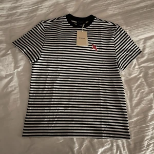 Axel arigato t-shirt. Storlek M. - Helt ny Axel arigato t-shirt storlek M. Svart och vit randig. True to size. Regular fit. Passar bra på mig som är 180cm 73kg. Bor på Södermalm.