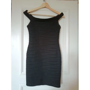 Svart off-shoulder klänning  - Svart, tight off-shoulder klänning från Nelly. Storlek M men liten i storlek, skulle säga den passar en XS. Använd men i gott skick, någon tråddragning (se sista bilden).