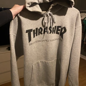 Grå thrasher hoodie - Säljer då jag aldrig använder längre. Väl använd men i väldigt gott skick! Inga fläckar eller märken. Denna är i L men passar mig som annars bär s/m
