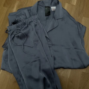 Satin pyjamas  - Satin pyjamas från h&m! Skjorta och långa byxor. Färgen är grå, syns bättre på bild två. Aldrig använt för har inte fått tillfälle. Köp hela setet för 200 kr <3 klicka på köp nu 