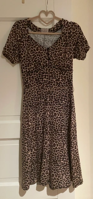 Klänning - Jättefin leopardklönning i storlek S, totallängd 99 cm. Lätt utställd i modellen, trikå med tre knappar upptill i dekolletaget. Leopardfärgad. Nyskick. Använd 2 ggr.