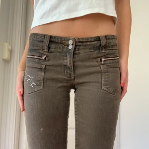 Bruna jeans - SJUKT coola jeans med rinestones på sidan. De är lågmidjade och från MAPP! Inneben: 80 cm. Midja rakt över: ca 35 cm. Dom är bruna!