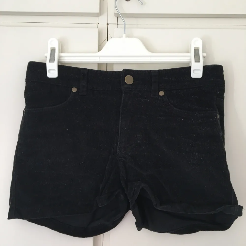 Korta svarta manchestershorts med fickor fram och bak. Guldknappar. Från H&M. Storlek 32.. Shorts.