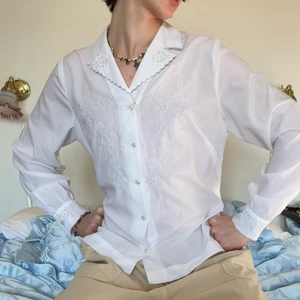 Vintage vit broderad blommig skjorta - Vit vintage skjorta med broderade snirkliga blommor 🐚 Den sötaste skjortan någonsin! Broderierna är att dö för och de är både på bröstet, ärmarna och på kragen! Jag älskar också att kragen är volang inspirerad! En så tidlös skjorta som gör din garderob mycket intressantare! :D