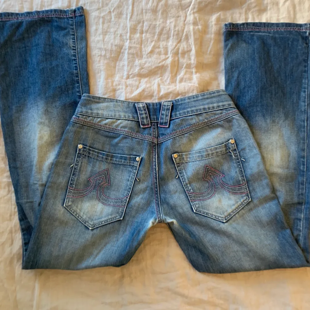 Assnygga lågmidjade jeans från Vila! Bootcut med rosa sömmar och gullig knapp. Waist 27/ St S. Har tyvärr ett litet hål i grenen, därav priset. Midjemått 28 och ytterbensmått 102 . Jeans & Byxor.